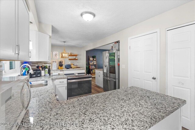 992 Touraine Ave, East Lansing, MI 48823 - kitchen with appliances with stainless steel finishes, a sink, a textured ceiling, light stone counters, and white cabinets