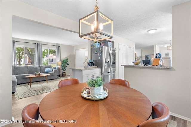 992 Touraine Ave, East Lansing, MI 48823 - dining space with light wood finished floors, a chandelier, baseboards, and a textured ceiling