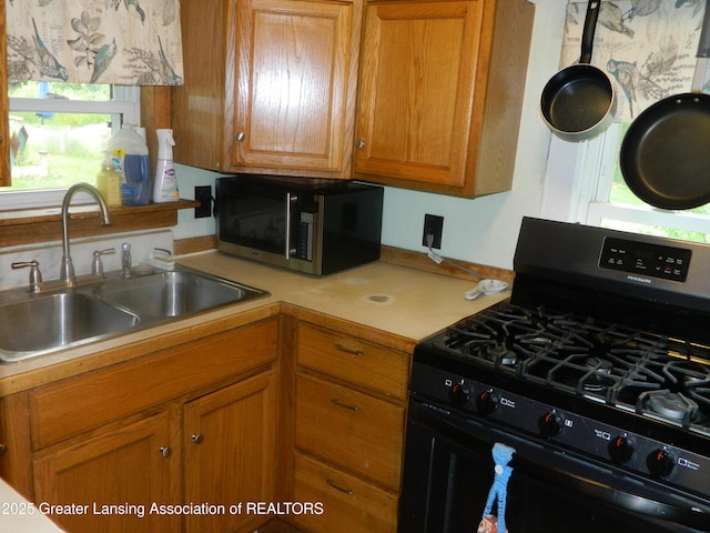 161 Okemos Rd, Mason, MI 48854 - kitchen with gas stove, a sink, stainless steel microwave, light countertops, and brown cabinets