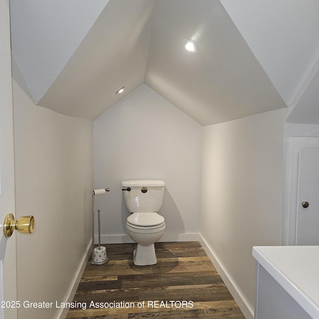 405 E Shaw St, Charlotte, MI 48813 - bathroom featuring toilet, vaulted ceiling, wood finished floors, baseboards, and vanity