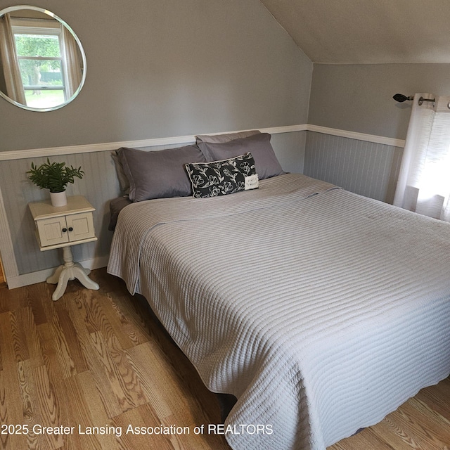 405 E Shaw St, Charlotte, MI 48813 - bedroom featuring wood finished floors, wainscoting, and lofted ceiling