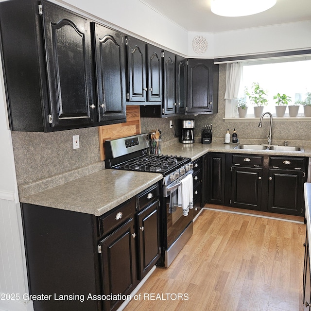 405 E Shaw St, Charlotte, MI 48813 - kitchen featuring stainless steel gas stove, a sink, dark cabinets, and light countertops