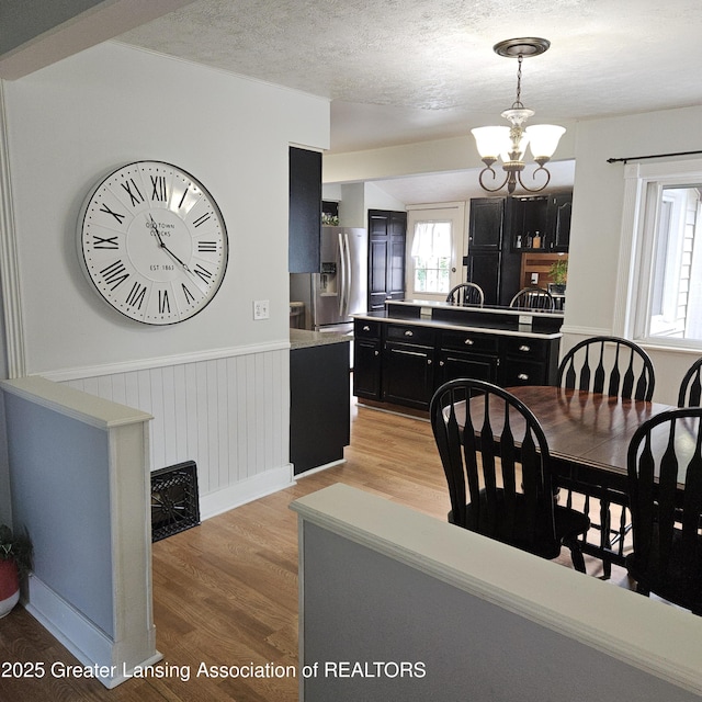 405 E Shaw St, Charlotte, MI 48813 - dining room with light wood-style floors, a chandelier, wainscoting, plenty of natural light, and a textured ceiling
