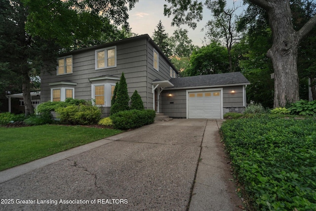 932 Sunset Ln, East Lansing, MI 48823 - view of front of home with concrete driveway, an attached garage, and a front lawn