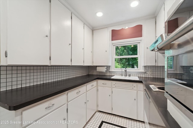 932 Sunset Ln, East Lansing, MI 48823 - kitchen with tasteful backsplash, dark countertops, white cabinetry, recessed lighting, and oven