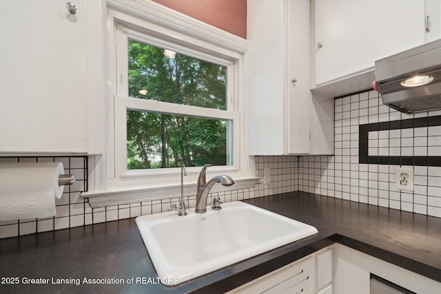 932 Sunset Ln, East Lansing, MI 48823 - kitchen with dark countertops, white cabinets, decorative backsplash, and healthy amount of natural light