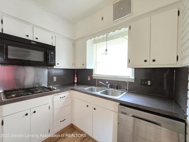 812 Westmoreland Ave, Lansing, MI 48915 - kitchen featuring appliances with stainless steel finishes, a sink, dark countertops, decorative backsplash, and light wood-type flooring