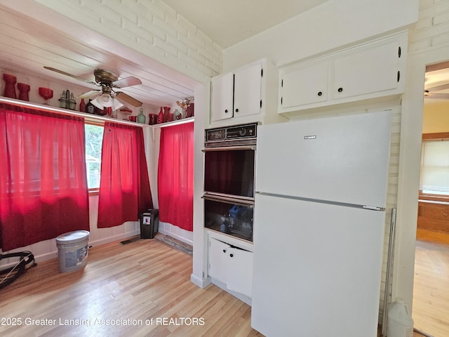 812 Westmoreland Ave, Lansing, MI 48915 - kitchen featuring freestanding refrigerator, black oven, a ceiling fan, light wood-style floors, and white cabinetry
