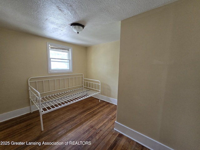 812 Westmoreland Ave, Lansing, MI 48915 - unfurnished bedroom featuring baseboards, wood finished floors, and a textured ceiling