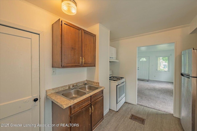 629 Emily Ave, Lansing, MI 48910 - kitchen featuring white gas range oven, a sink, freestanding refrigerator, light countertops, and under cabinet range hood