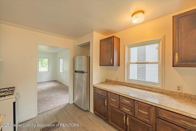 629 Emily Ave, Lansing, MI 48910 - kitchen featuring freestanding refrigerator, light countertops, light wood-style floors, gas range gas stove, and crown molding