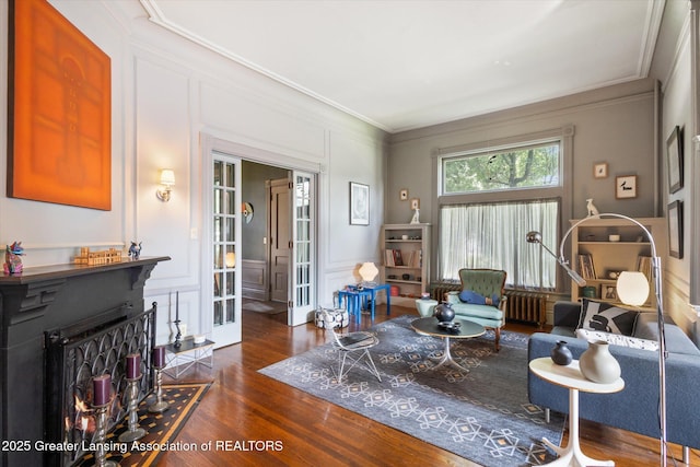 1035 N Capitol Ave, Lansing, MI 48906 - living area with a warm lit fireplace, dark wood finished floors, radiator heating unit, a decorative wall, and ornamental molding