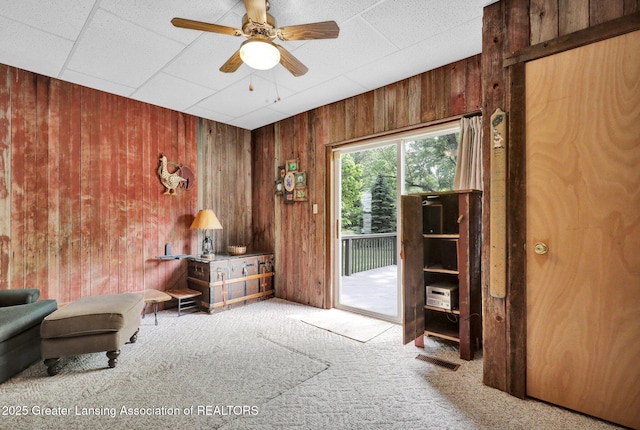 8767 Corrison Rd, Grand Ledge, MI 48837 - sitting room featuring wooden walls, carpet floors, a ceiling fan, and a paneled ceiling