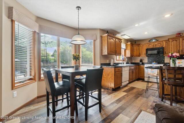 2020 Sunset Dr, Owosso, MI 48867 - kitchen with white appliances, light wood-style flooring, dark countertops, brown cabinetry, and recessed lighting