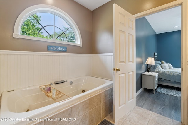 2020 Sunset Dr, Owosso, MI 48867 - bathroom with connected bathroom, plenty of natural light, a tub with jets, wainscoting, and tile patterned floors