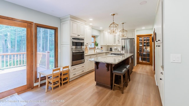 1117 Windreef Cir, Okemos, MI 48864 - kitchen with appliances with stainless steel finishes, a center island, a kitchen bar, light stone countertops, and light wood-style flooring