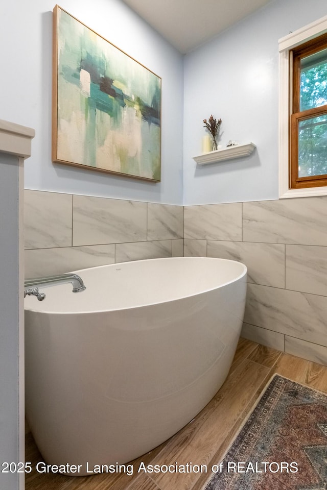 1117 Windreef Cir, Okemos, MI 48864 - bathroom featuring tile walls, a freestanding tub, wood finished floors, and wainscoting