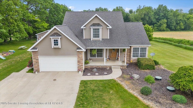 4905 E Green Rd, Saint Johns, MI 48879 - view of front of house with covered porch, concrete driveway, a garage, stone siding, and a front lawn