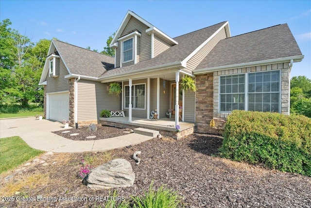 4905 E Green Rd, Saint Johns, MI 48879 - view of front facade with a porch, roof with shingles, stone siding, driveway, and an attached garage