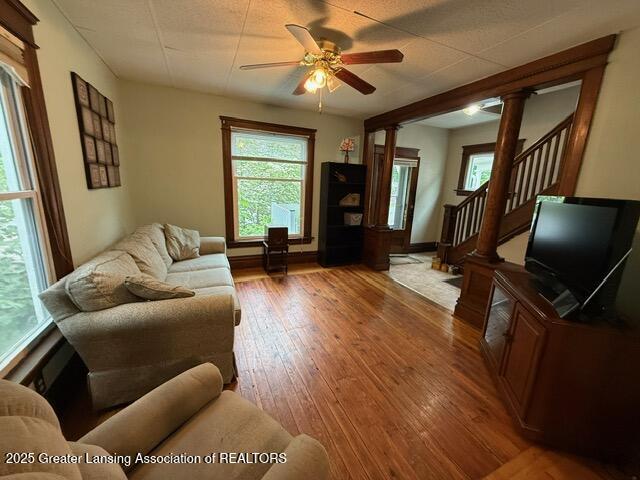 921 W Genesee St, Lansing, MI 48915 - living room featuring decorative columns, a ceiling fan, hardwood / wood-style floors, and stairs