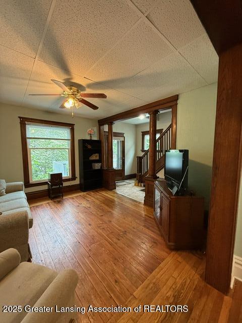 921 W Genesee St, Lansing, MI 48915 - living area featuring decorative columns, hardwood / wood-style floors, ceiling fan, and stairway