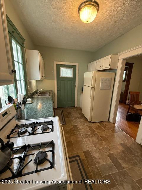 921 W Genesee St, Lansing, MI 48915 - kitchen with white appliances, a textured ceiling, white cabinetry, and dark stone finish flooring
