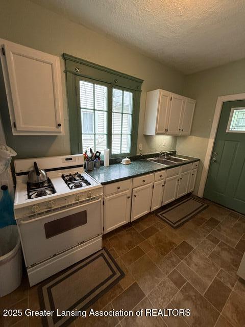 921 W Genesee St, Lansing, MI 48915 - kitchen with white gas range, white cabinetry, plenty of natural light, and a textured ceiling