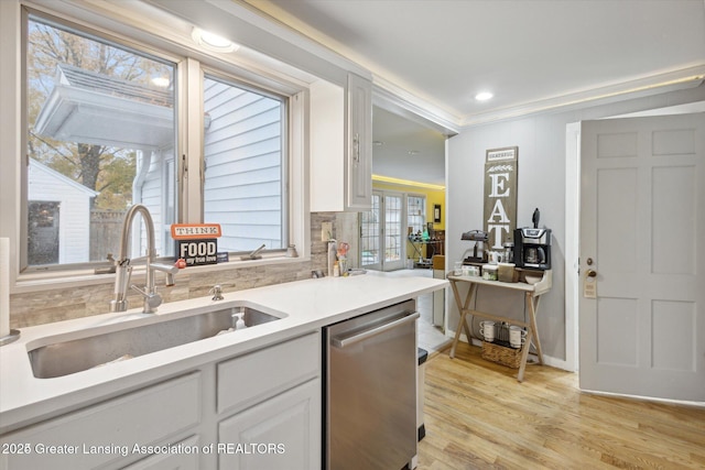 350 N Marshall Ave, Marshall, MI 49068 - kitchen with stainless steel dishwasher, light countertops, light wood-style floors, white cabinetry, and backsplash