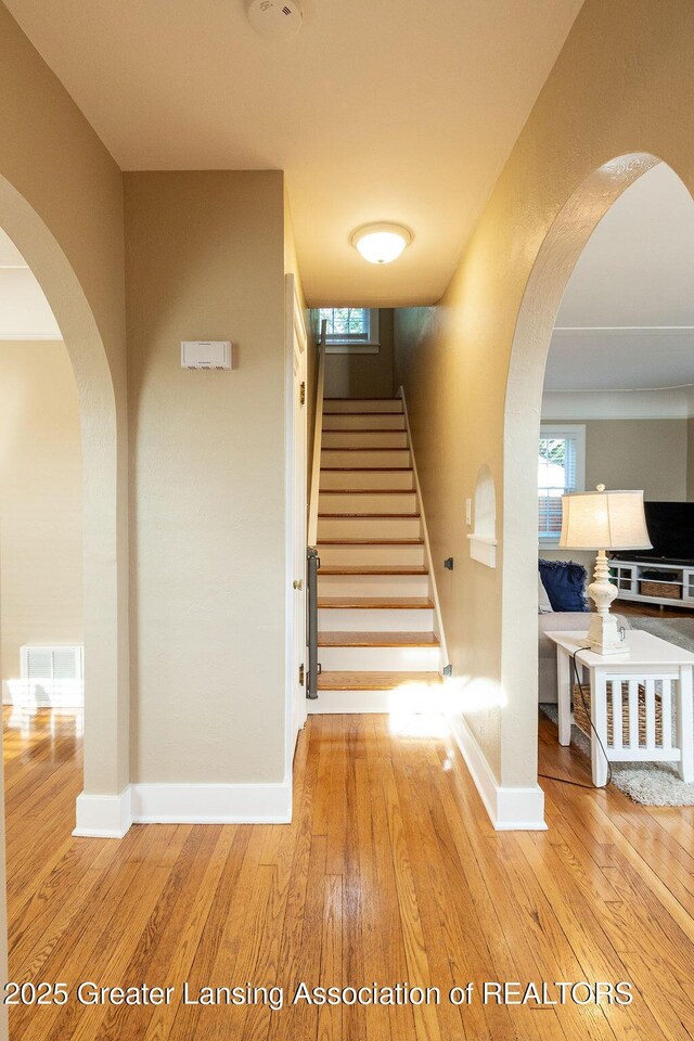 720 N Fairview Ave, Lansing, MI 48912 - staircase with hardwood / wood-style flooring, arched walkways, and healthy amount of natural light