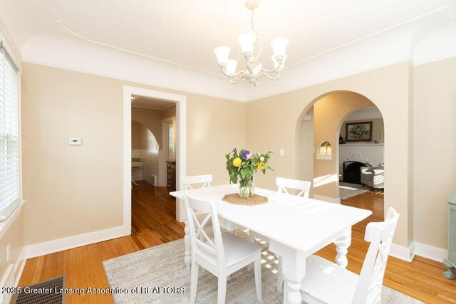 720 N Fairview Ave, Lansing, MI 48912 - dining area featuring a chandelier, arched walkways, light wood-style floors, and crown molding