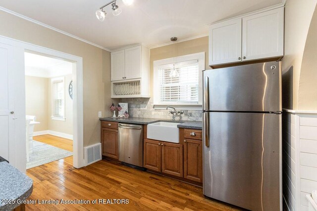 720 N Fairview Ave, Lansing, MI 48912 - kitchen with appliances with stainless steel finishes, dark wood-type flooring, backsplash, crown molding, and brown cabinetry