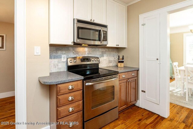 720 N Fairview Ave, Lansing, MI 48912 - kitchen with appliances with stainless steel finishes, wood finished floors, tasteful backsplash, dark countertops, and white cabinetry