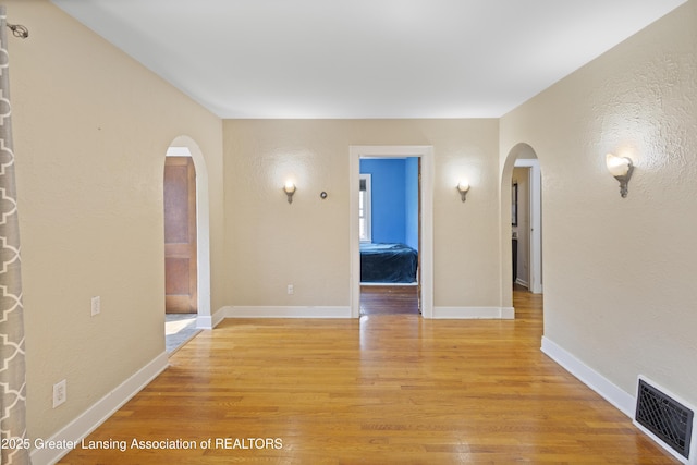 2335 Harding Ave, Lansing, MI 48910 - empty room with arched walkways and light wood finished floors