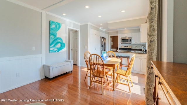 5939 Highgate Ave, East Lansing, MI 48823 - dining area with light wood-style flooring, crown molding, recessed lighting, and a wainscoted wall