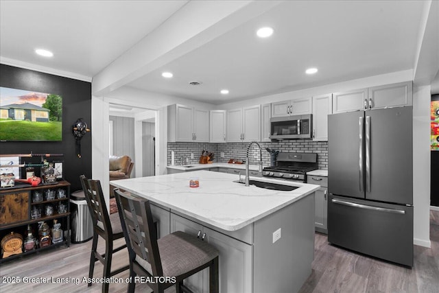3707 W Michigan Ave, Lansing, MI 48917 - kitchen featuring stainless steel appliances, light stone countertops, light wood finished floors, a kitchen breakfast bar, and recessed lighting
