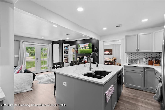 3707 W Michigan Ave, Lansing, MI 48917 - kitchen featuring gray cabinetry, tasteful backsplash, black dishwasher, a center island with sink, and wood finished floors