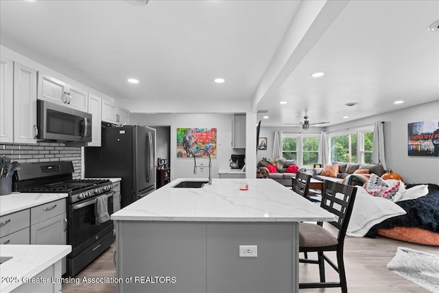 3707 W Michigan Ave, Lansing, MI 48917 - kitchen with stainless steel appliances, open floor plan, light stone countertops, light wood-style floors, and a kitchen breakfast bar
