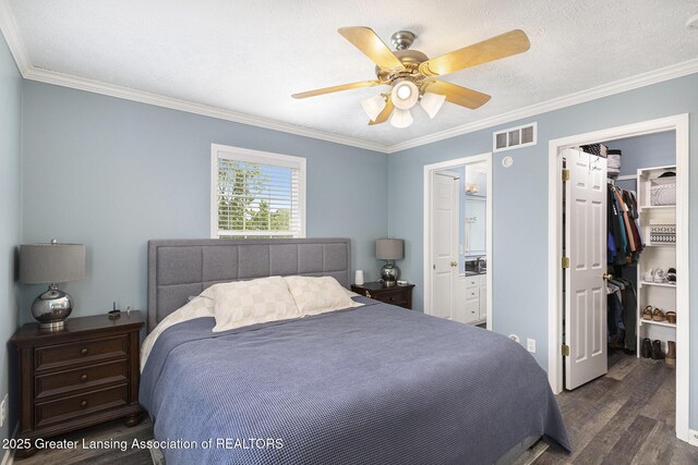 491 Anhinga Dr, East Lansing, MI 48823 - bedroom featuring dark wood finished floors, crown molding, a walk in closet, a closet, and ceiling fan