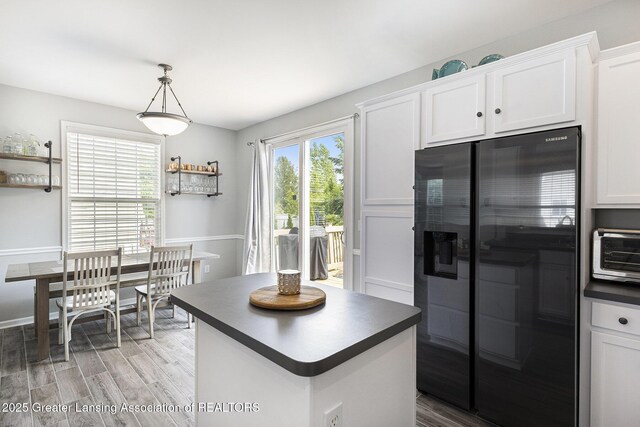 491 Anhinga Dr, East Lansing, MI 48823 - kitchen featuring fridge with ice dispenser, dark countertops, light wood-style flooring, white cabinets, and a center island