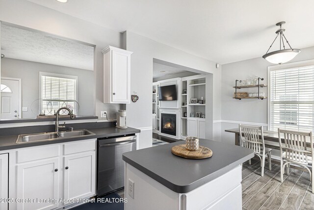 491 Anhinga Dr, East Lansing, MI 48823 - kitchen featuring dishwasher, dark countertops, white cabinets, a lit fireplace, and pendant lighting