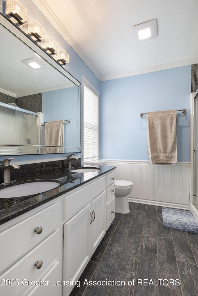 491 Anhinga Dr, East Lansing, MI 48823 - full bathroom featuring double vanity, crown molding, wainscoting, a shower stall, and wood finished floors