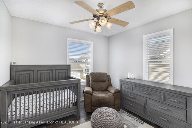 491 Anhinga Dr, East Lansing, MI 48823 - bedroom with multiple windows, a crib, wood finished floors, and a ceiling fan