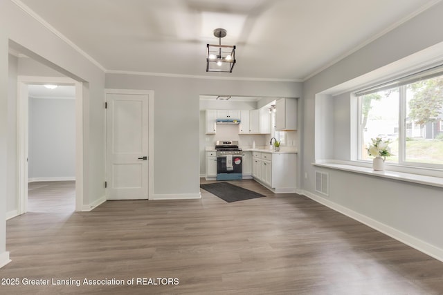1041 Parker St, Lansing, MI 48912 - kitchen featuring stainless steel stove, white cabinets, ornamental molding, light countertops, and light wood-style flooring