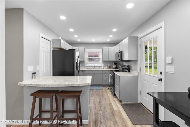 2914 W Holmes Rd, Lansing, MI 48911 - kitchen with freestanding refrigerator, stainless steel range with electric cooktop, gray cabinets, a peninsula, and a breakfast bar area