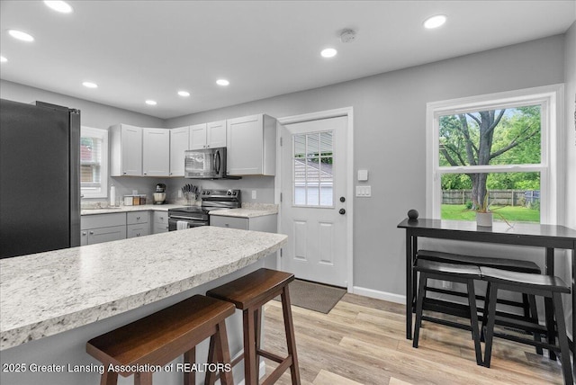 2914 W Holmes Rd, Lansing, MI 48911 - kitchen featuring appliances with stainless steel finishes, light countertops, a kitchen breakfast bar, recessed lighting, and light wood-style flooring