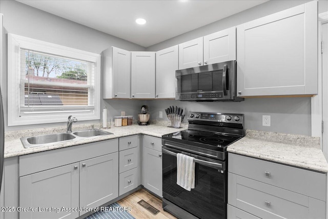 2914 W Holmes Rd, Lansing, MI 48911 - kitchen with electric range, stainless steel microwave, light wood-style floors, recessed lighting, and gray cabinets