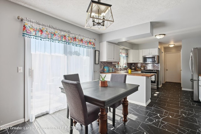 1234 Lamb Rd, Mason, MI 48854 - dining space featuring a textured ceiling, a chandelier, and dark marble finish floors