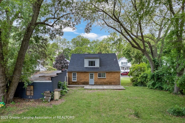 229 Rockingham Ave, Alma, MI 48801 - back of house with a wooden deck, a chimney, a lawn, and brick siding