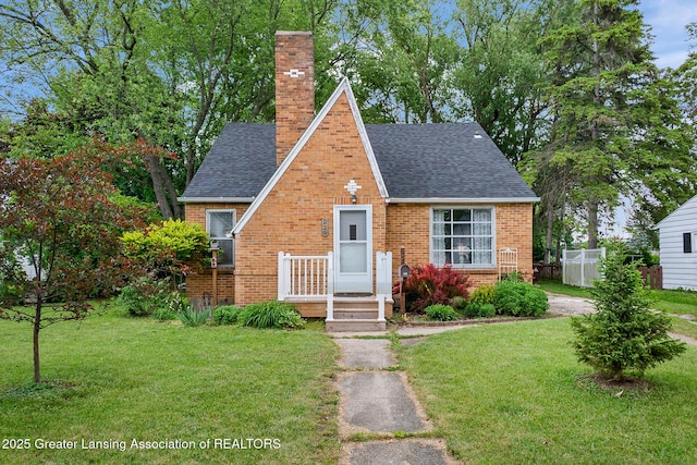 229 Rockingham Ave, Alma, MI 48801 - tudor home featuring roof with shingles, a chimney, and brick siding