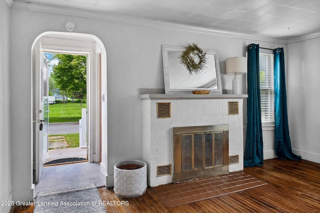 229 Rockingham Ave, Alma, MI 48801 - unfurnished living room with wood finished floors, a fireplace, crown molding, plenty of natural light, and arched walkways